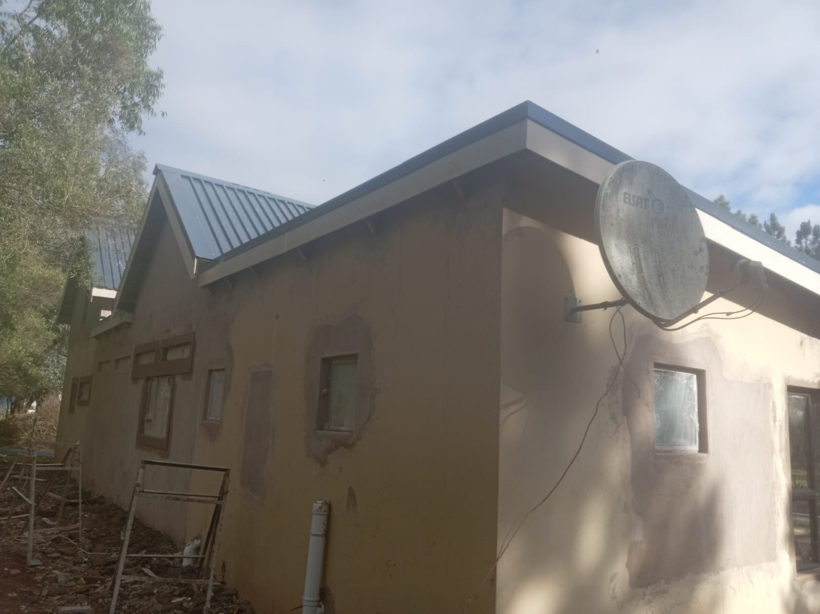 Plastered house exterior beneath a metal pitched roof